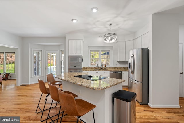 kitchen featuring stainless steel appliances, light wood-style floors, white cabinetry, and a breakfast bar area