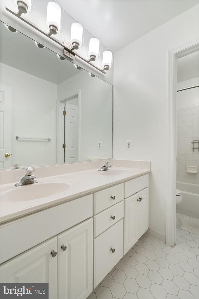 full bath featuring tile patterned floors, a sink, double vanity, and toilet