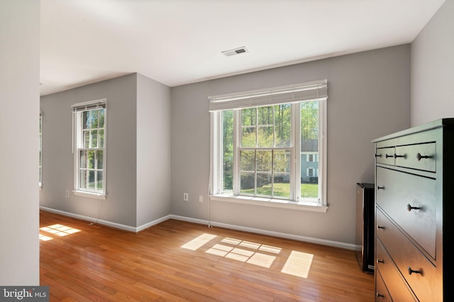 unfurnished bedroom featuring baseboards, multiple windows, and visible vents