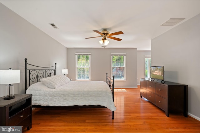 bedroom featuring light wood finished floors, baseboards, visible vents, and ceiling fan