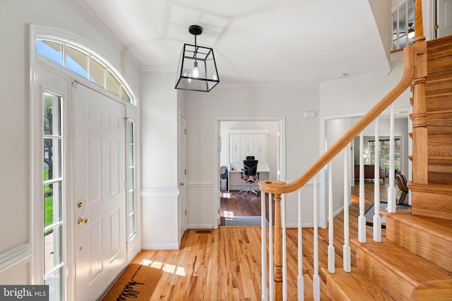 foyer entrance with light wood-type flooring, baseboards, stairs, and ornamental molding