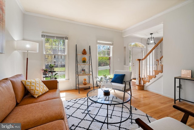 living area featuring baseboards, wood finished floors, stairs, and crown molding