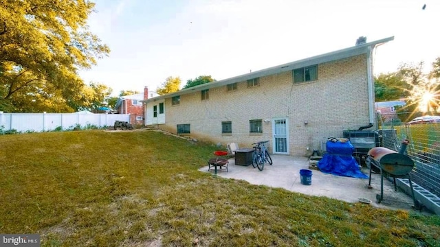 rear view of house featuring a fenced backyard, a patio, brick siding, and a lawn
