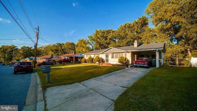 ranch-style house with a chimney, fence, concrete driveway, a front yard, and a carport