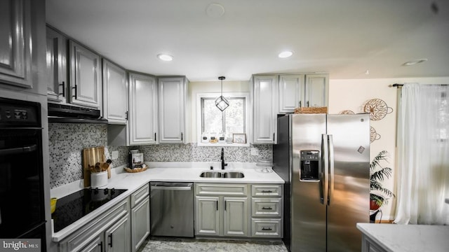 kitchen featuring light countertops, a sink, black appliances, under cabinet range hood, and gray cabinetry