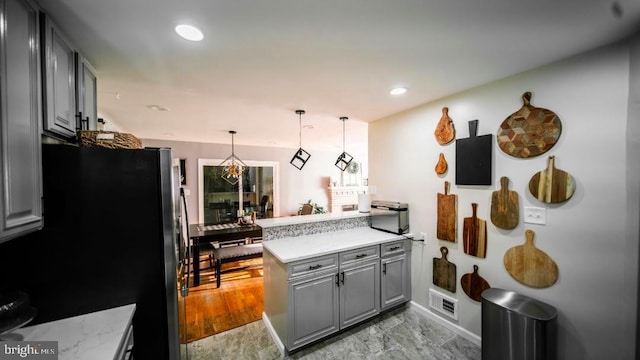 kitchen featuring freestanding refrigerator, recessed lighting, marble finish floor, a peninsula, and gray cabinets