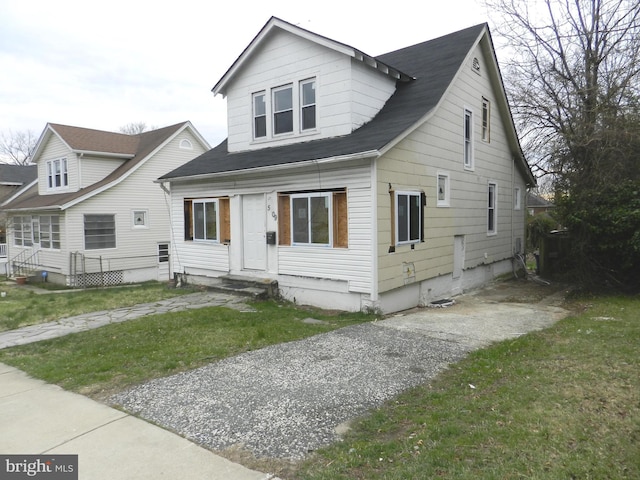 bungalow-style home featuring a shingled roof, a front yard, and entry steps