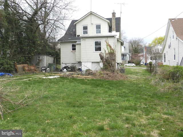rear view of house with a chimney and a yard
