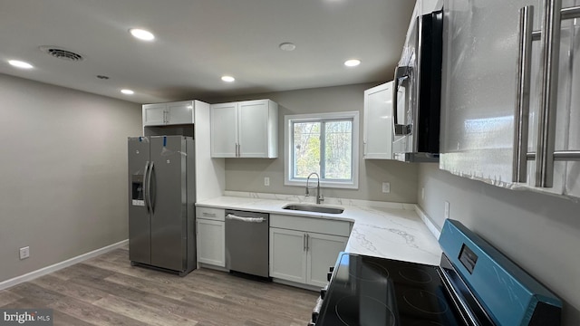 kitchen with recessed lighting, light stone countertops, stainless steel appliances, and a sink