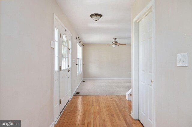 interior space featuring light wood finished floors, baseboards, and a ceiling fan