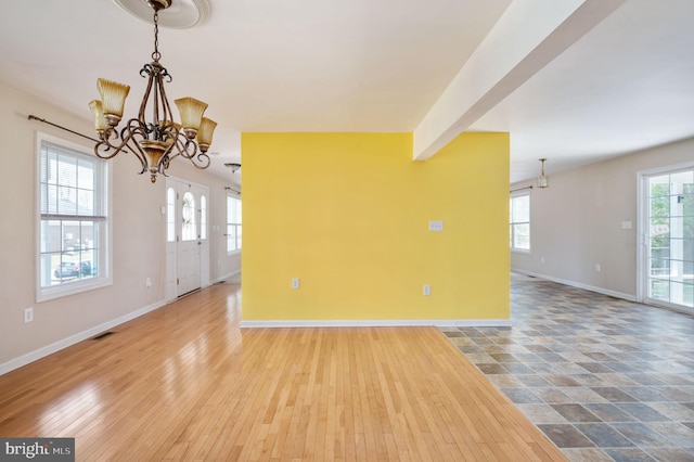 unfurnished room featuring visible vents, baseboards, a notable chandelier, and wood finished floors