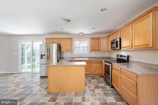 kitchen featuring recessed lighting, a center island, stone finish floor, stainless steel appliances, and a sink