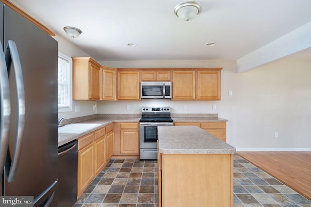 kitchen featuring a center island, light brown cabinets, a sink, light countertops, and stainless steel appliances