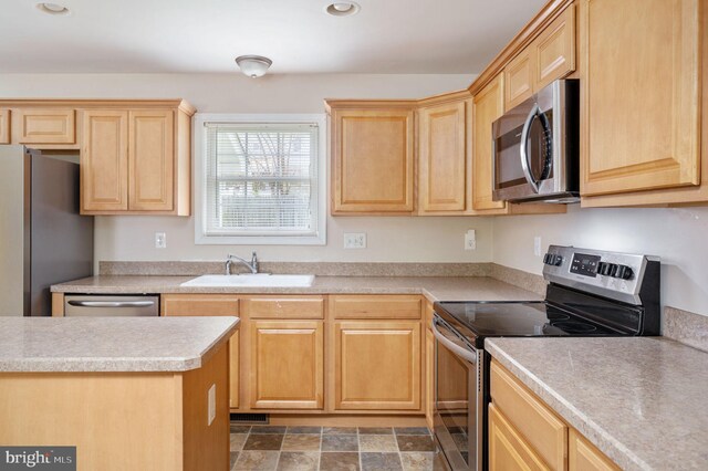 kitchen with light brown cabinetry, appliances with stainless steel finishes, and a sink