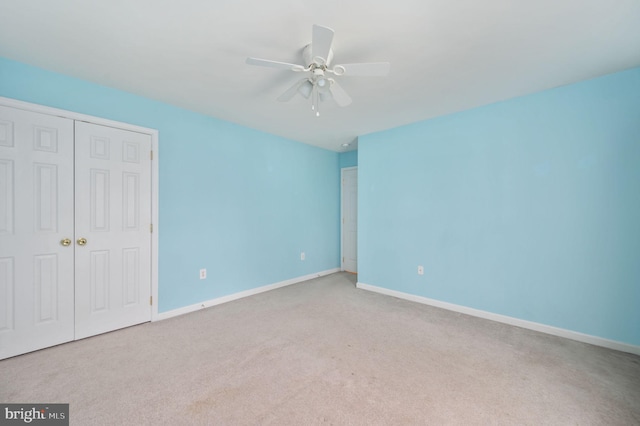 unfurnished bedroom with baseboards, carpet floors, ceiling fan, and a closet