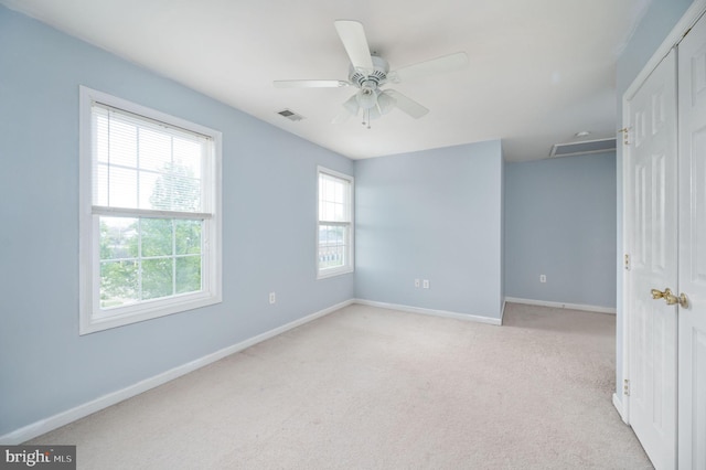unfurnished bedroom with light carpet, visible vents, baseboards, and a closet