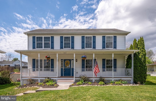 colonial home featuring a porch and a front yard