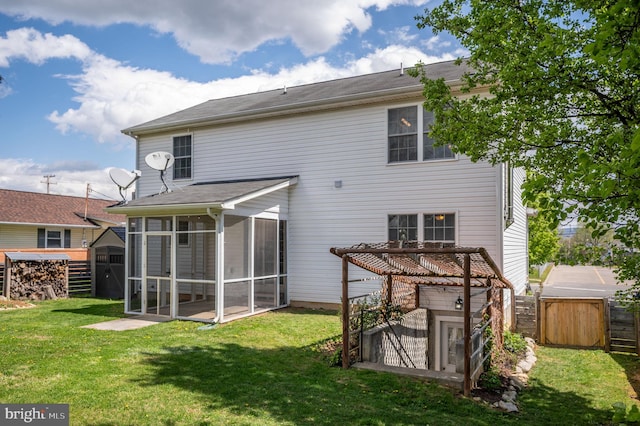 rear view of house featuring a sunroom, fence, an outdoor structure, and a lawn