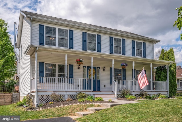 colonial home featuring a front yard and covered porch