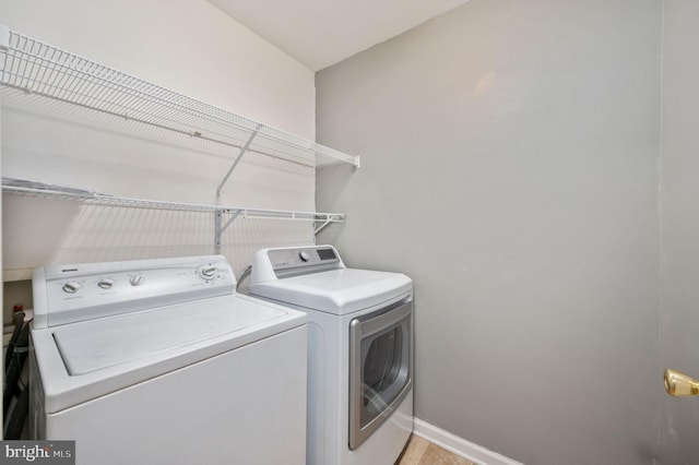 clothes washing area featuring washing machine and clothes dryer, laundry area, and baseboards