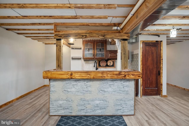 kitchen featuring light wood-style floors, glass insert cabinets, baseboards, and a sink