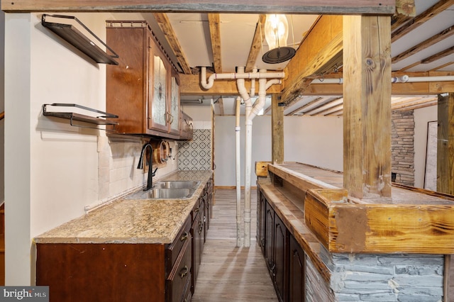 interior space with light countertops, wood finished floors, a sink, glass insert cabinets, and tasteful backsplash