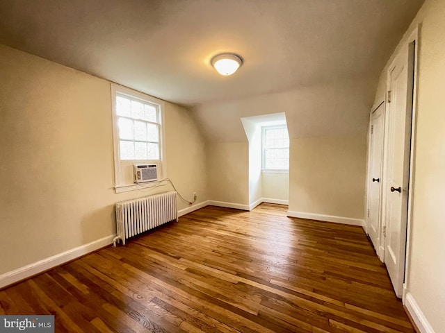bonus room with radiator heating unit, a healthy amount of sunlight, baseboards, and wood finished floors