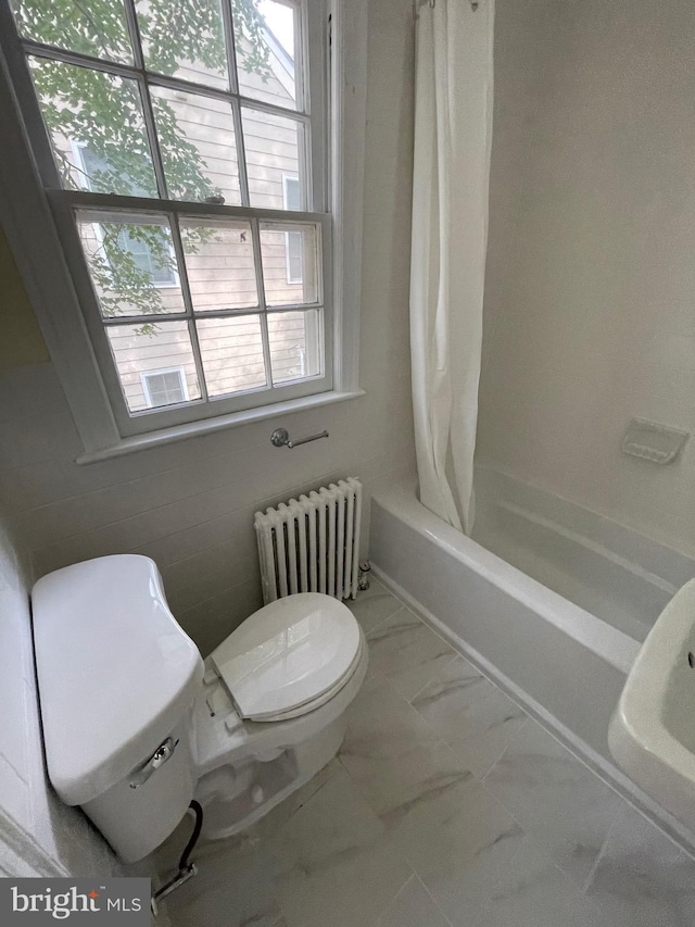 bathroom featuring radiator heating unit, shower / bath combo with shower curtain, marble finish floor, and toilet