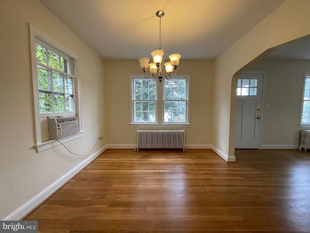 unfurnished dining area with radiator, wood finished floors, and a healthy amount of sunlight
