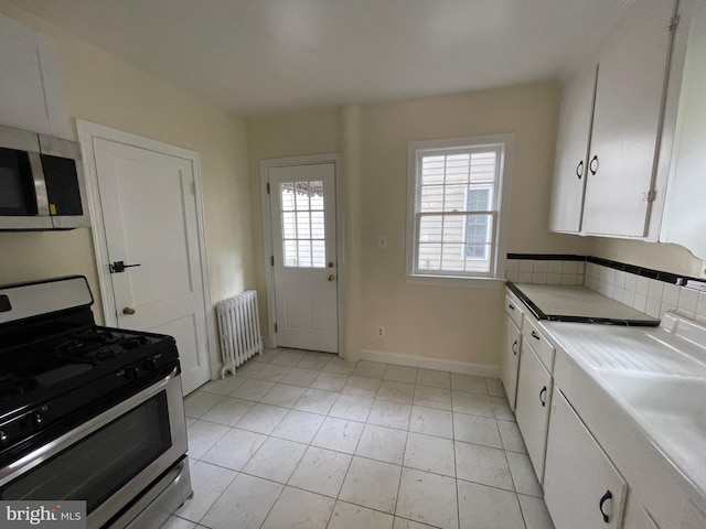 kitchen featuring radiator heating unit, white cabinetry, light countertops, stainless steel appliances, and baseboards