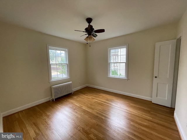 spare room with a wealth of natural light, radiator, and wood finished floors