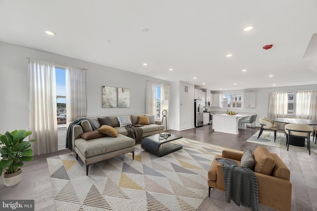 living area with a wealth of natural light, light wood-style flooring, and recessed lighting