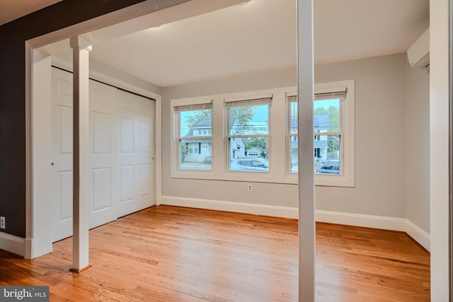 unfurnished bedroom featuring baseboards, decorative columns, and light wood-type flooring