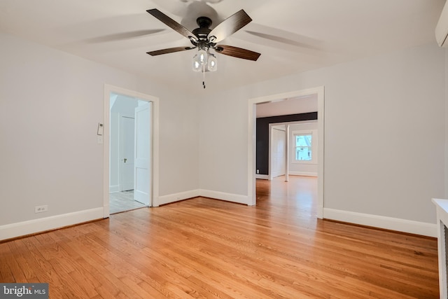 unfurnished room featuring baseboards, light wood-style floors, ceiling fan, and a wall unit AC