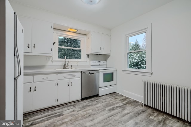 kitchen featuring white appliances, radiator heating unit, plenty of natural light, light countertops, and a sink