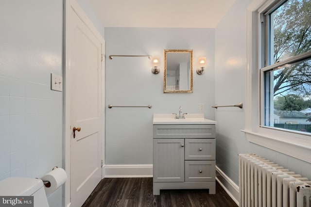 half bath featuring baseboards, wood finished floors, radiator, and vanity
