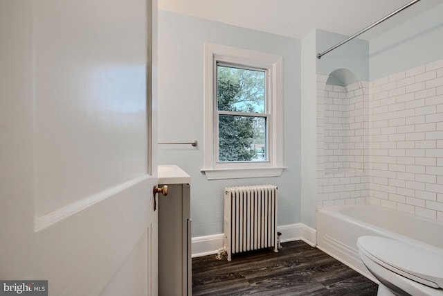 full bath with wood finished floors, vanity, toilet, radiator heating unit, and tub / shower combination