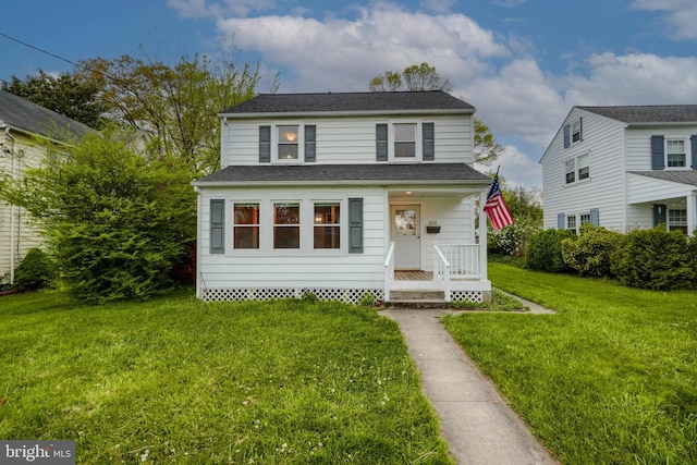 view of front of home with roof with shingles, covered porch, and a front lawn