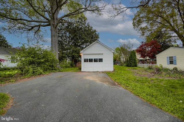 detached garage featuring fence and driveway