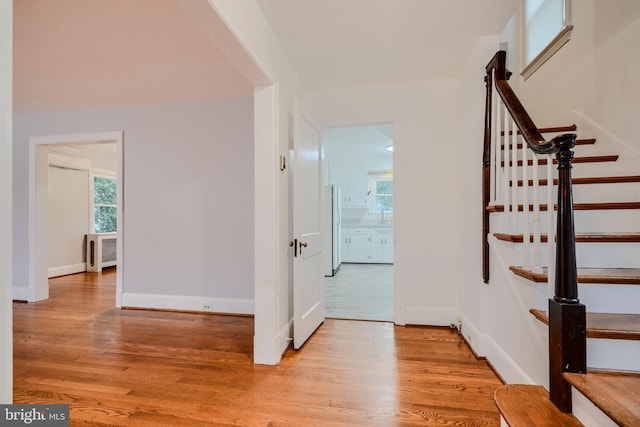 interior space featuring light wood-type flooring, stairs, baseboards, and a wall mounted AC
