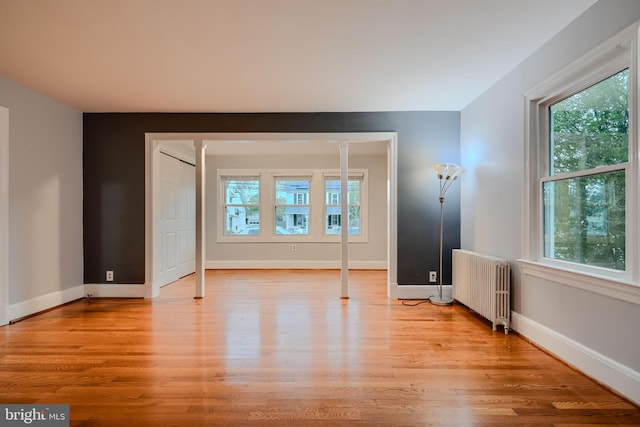 empty room with radiator heating unit, plenty of natural light, and light wood finished floors