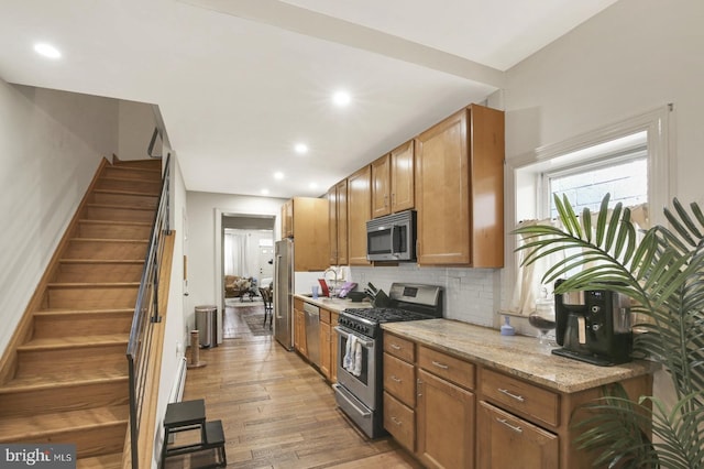 1240 Leopard St, Philadelphia, PA 19125 - kitchen with light wood finished floors, appliances with stainless steel finishes, decorative backsplash, and brown cabinetry