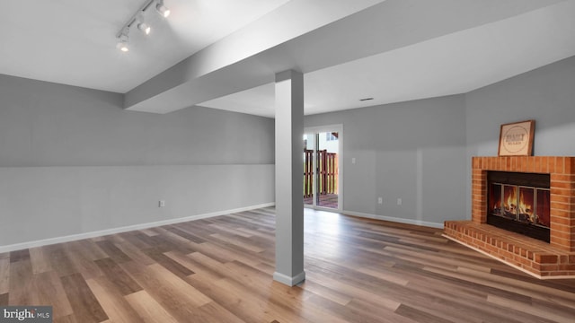 1315 Riverwood, Baltimore, MD 21226 - unfurnished living room featuring baseboards, a fireplace, rail lighting, and wood finished floors