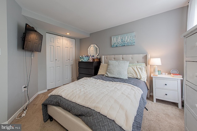 bedroom featuring light carpet, baseboards, and a closet