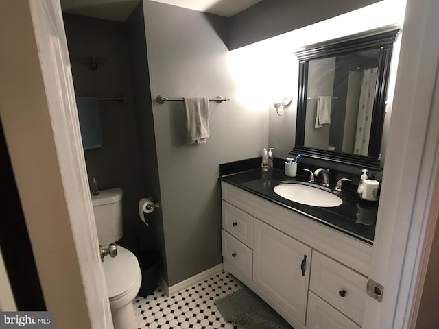 bathroom featuring baseboards, toilet, and vanity