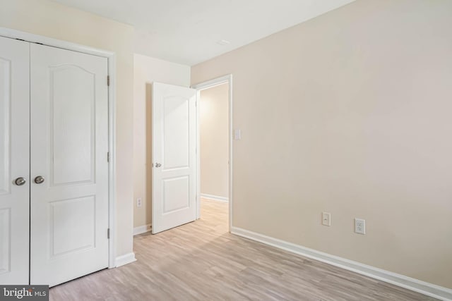 unfurnished bedroom featuring a closet, baseboards, and light wood-type flooring