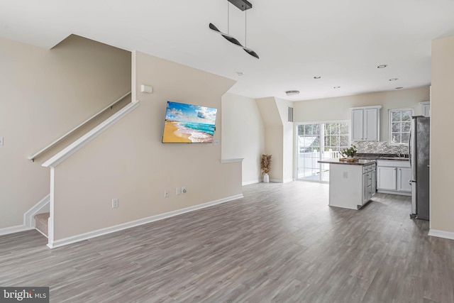 unfurnished living room featuring light wood-style floors, a ceiling fan, recessed lighting, stairway, and baseboards