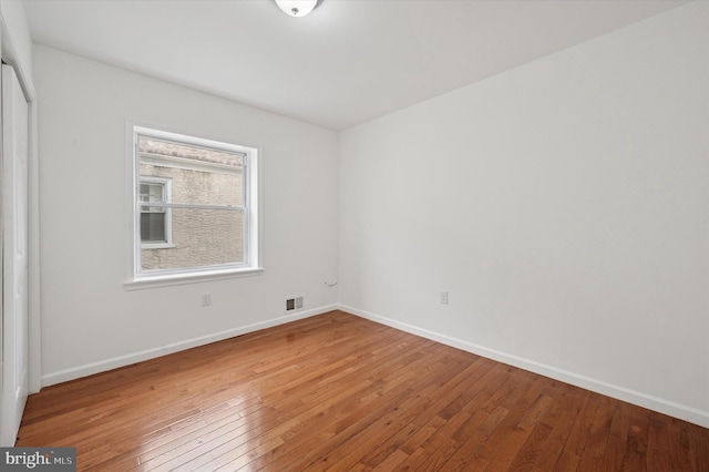 spare room with visible vents, baseboards, and hardwood / wood-style flooring
