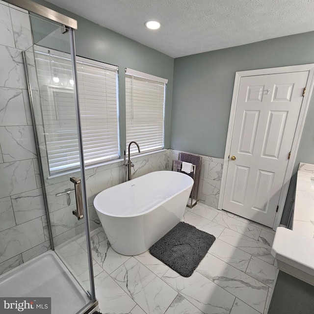 full bathroom with a freestanding tub, vanity, tile walls, a shower stall, and marble finish floor