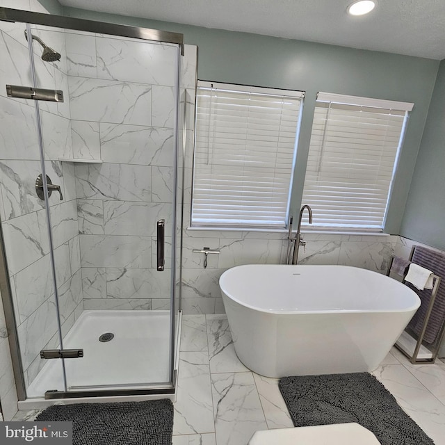 full bath with a freestanding bath, marble finish floor, tile walls, and a stall shower